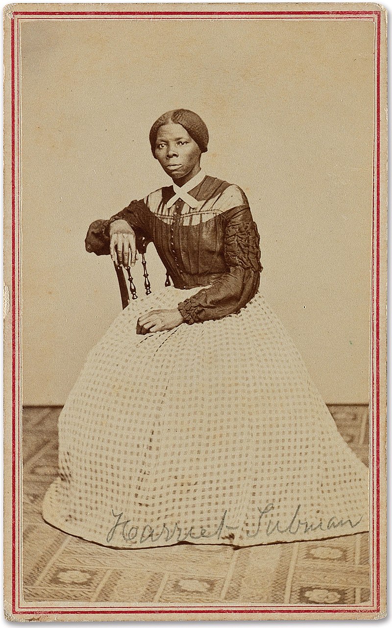 Harriet Tubman, sitting in chair, wearing a long-sleeved top and long skirt.